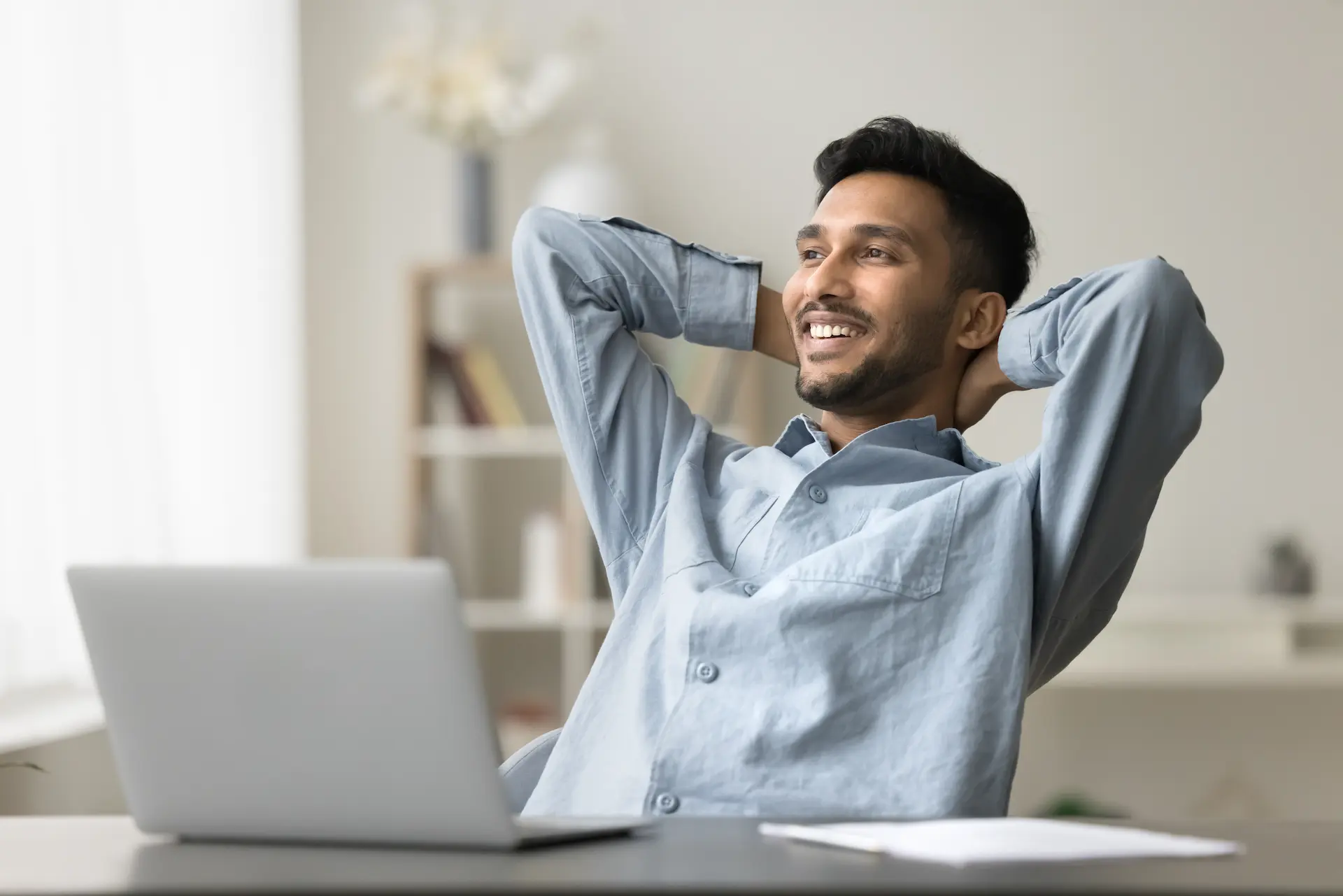 A man leaning back in his chair with a smile, reflecting a lean work culture that reduces mental waste and fosters satisfaction.