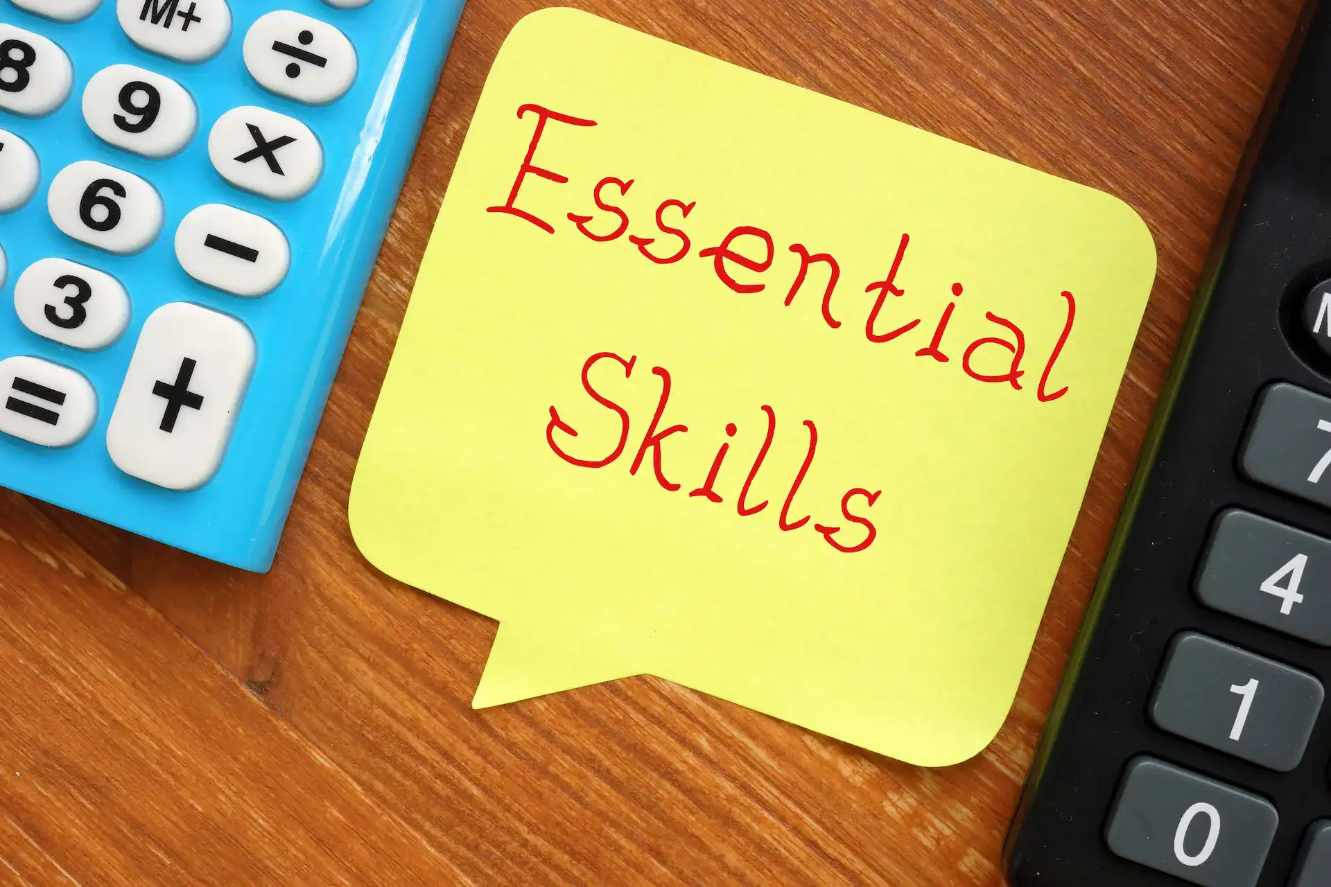 A calculator and a post-it note with the words "essential skills" written on it, showcasing the need to foster capabilities for successful organizational navigation.
