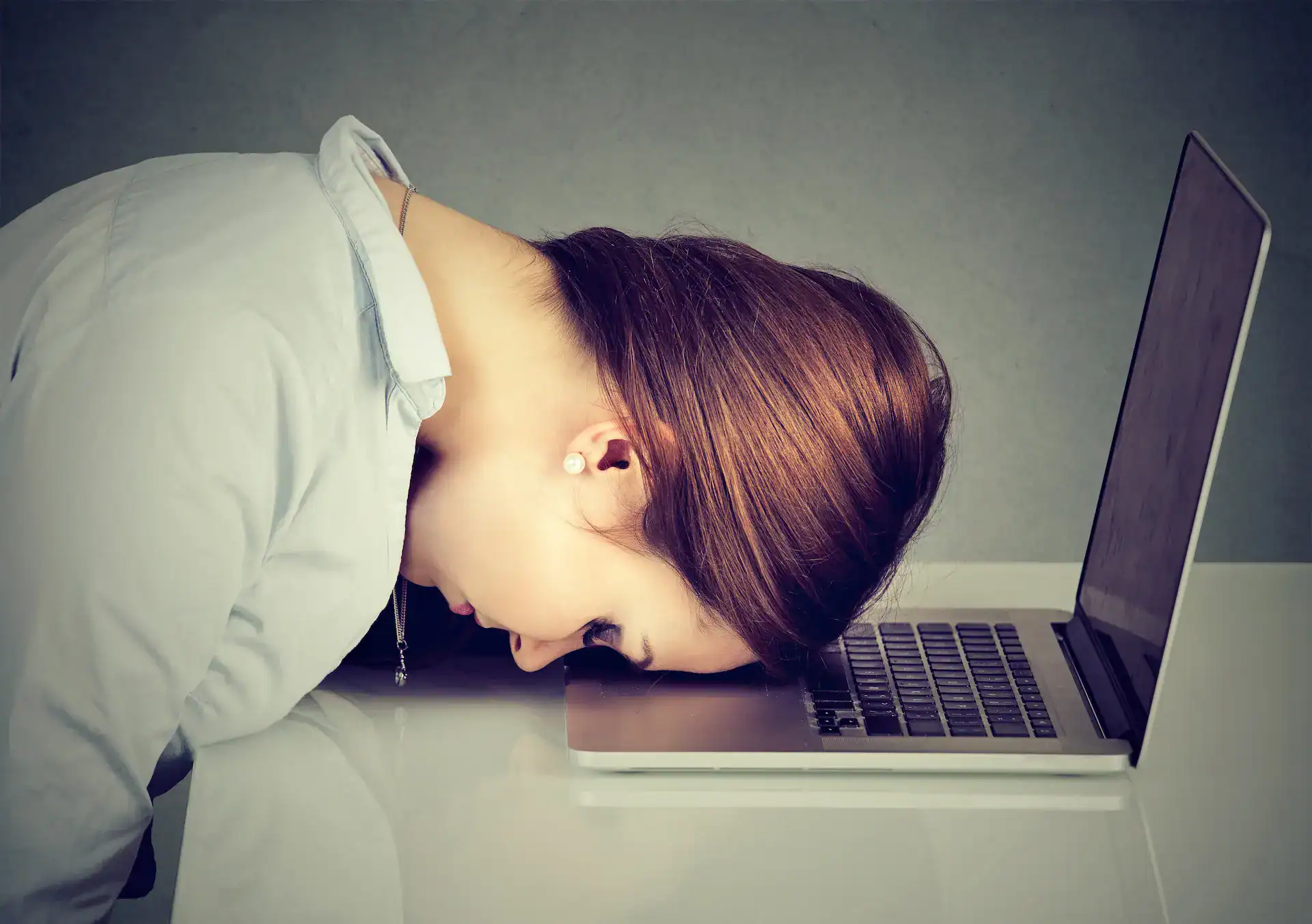 A woman with her head in on her laptop, tired of the voice in her head.