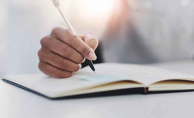 A woman jotting down ideas for their learning agenda in a notebook.