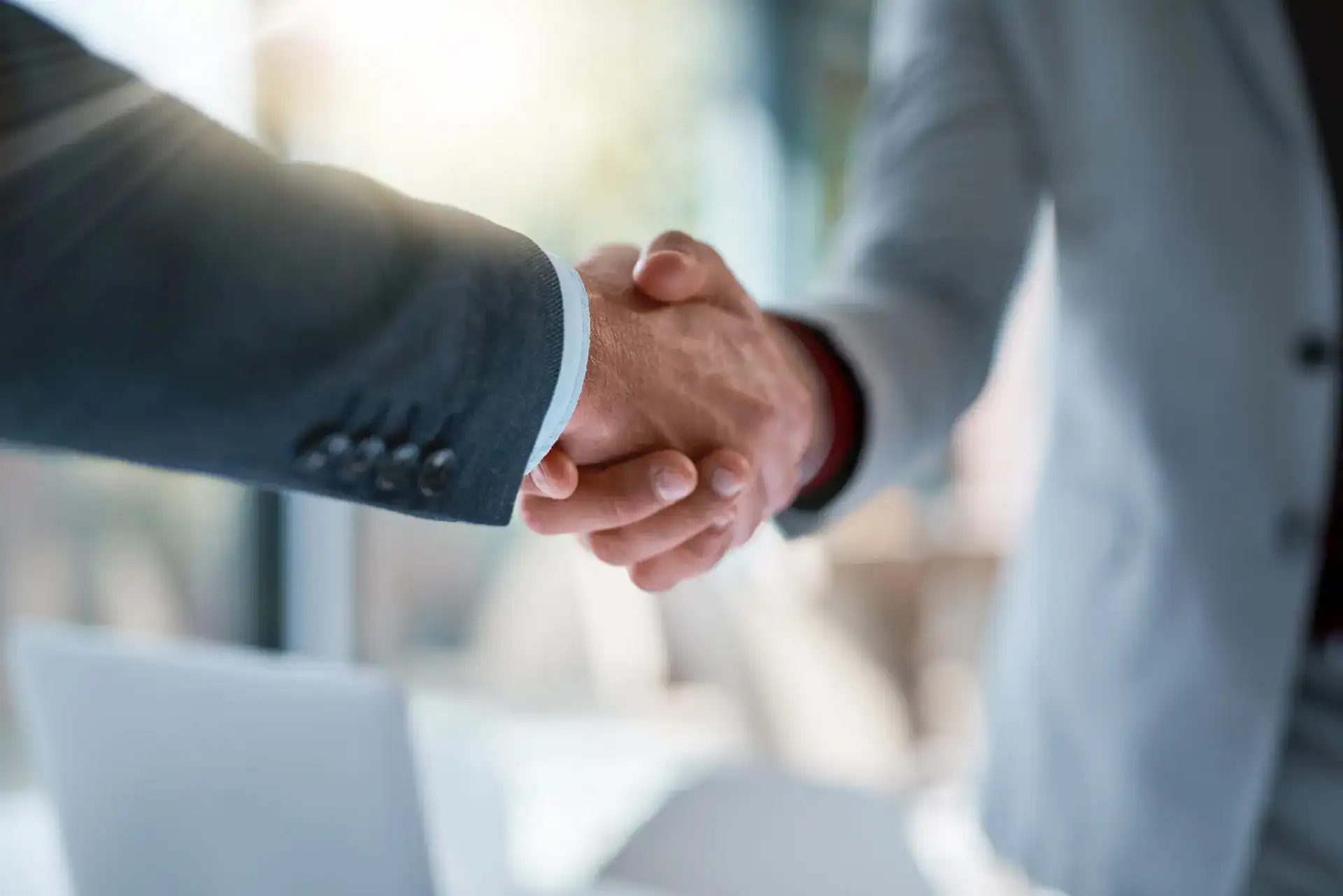 A close-up of two men shaking hands, symbolizing a strong professional alliance.