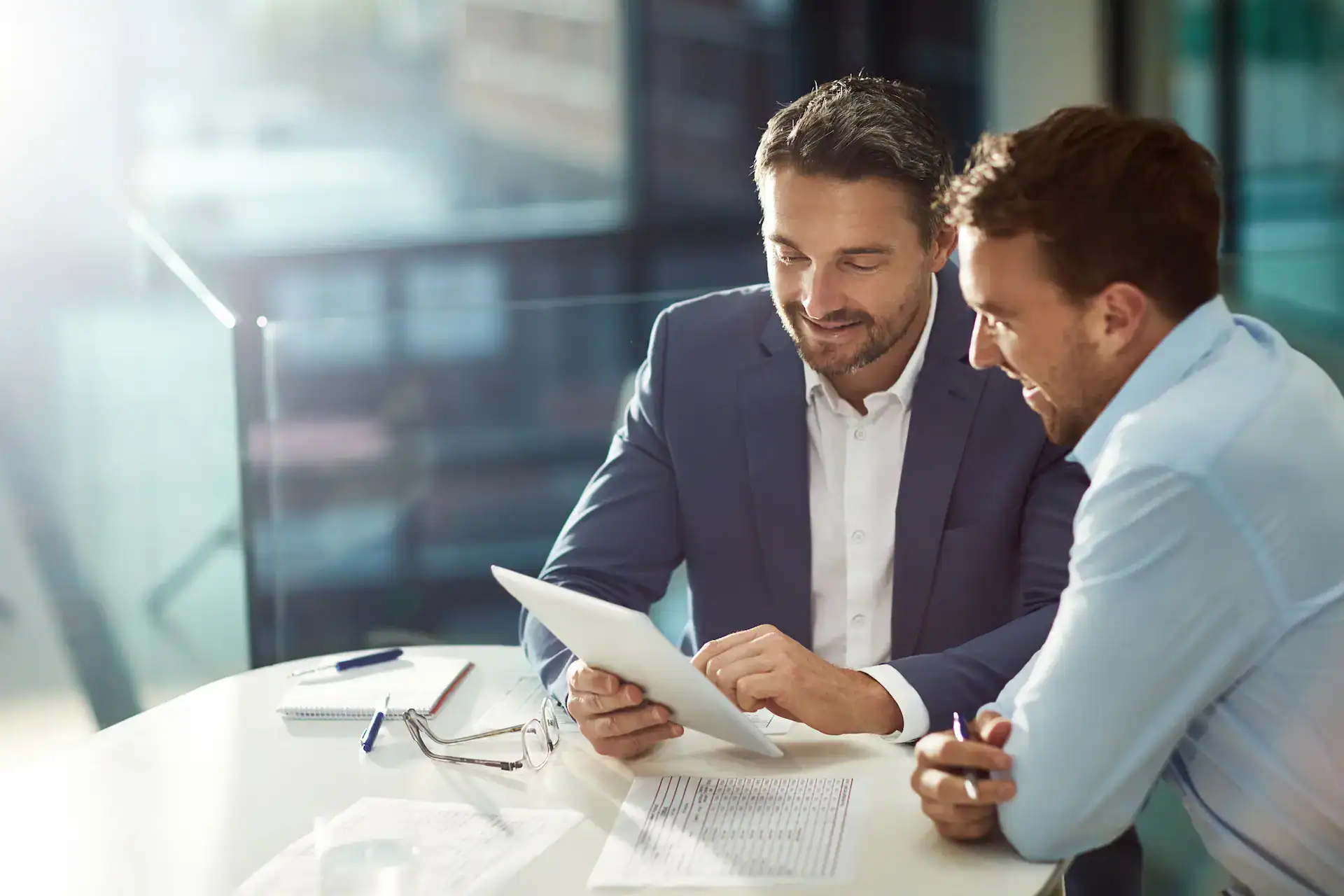 Two men collaborate over an iPad, working together as trusted allies.