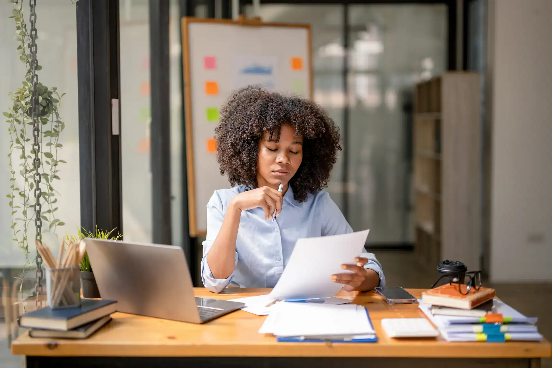 A professional woman sits at her desk reviewing documents as part of her goal-setting process for personal and career growth.