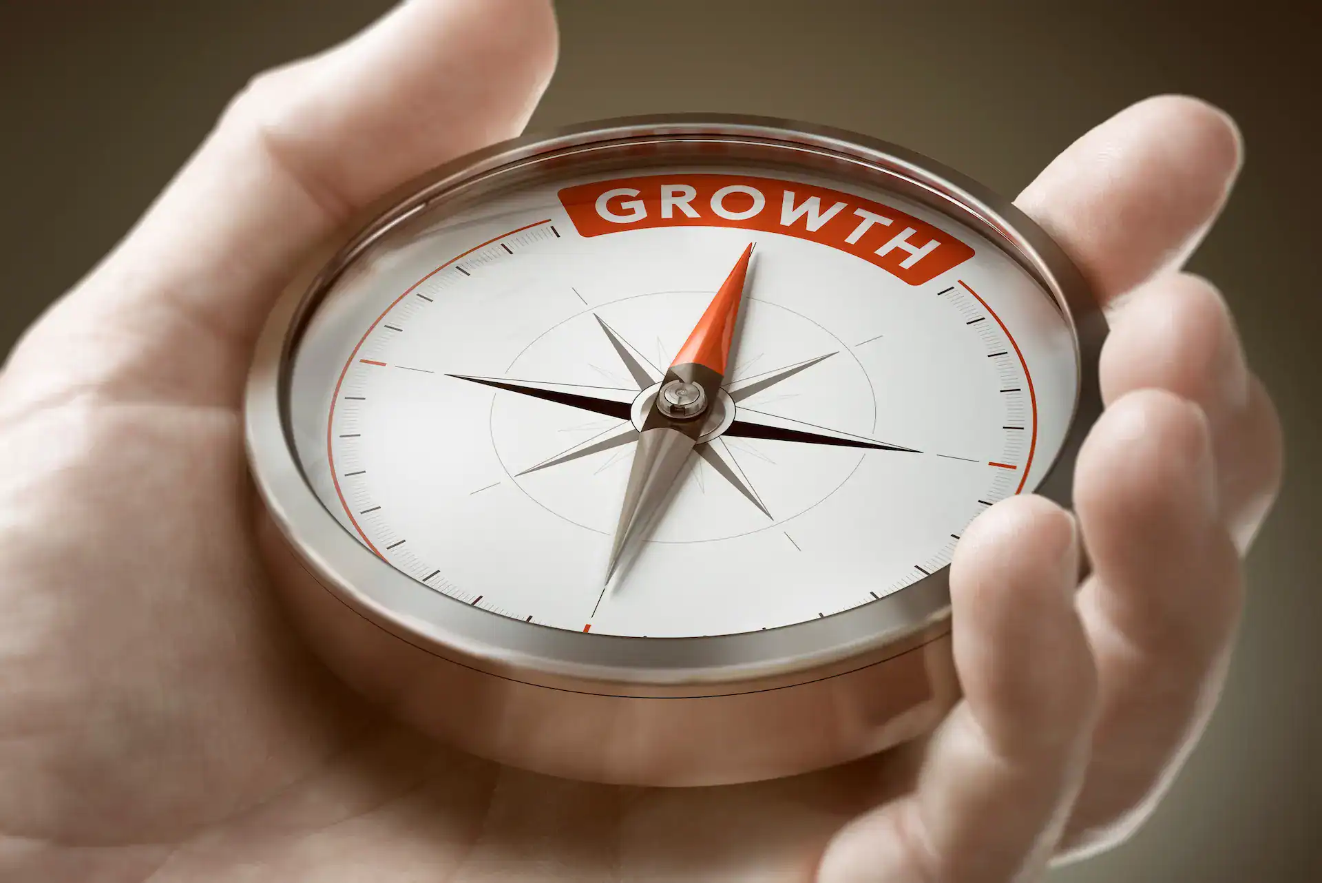 A person holds a compass marked “Growth” to symbolize direction and focus in goal setting for career development.