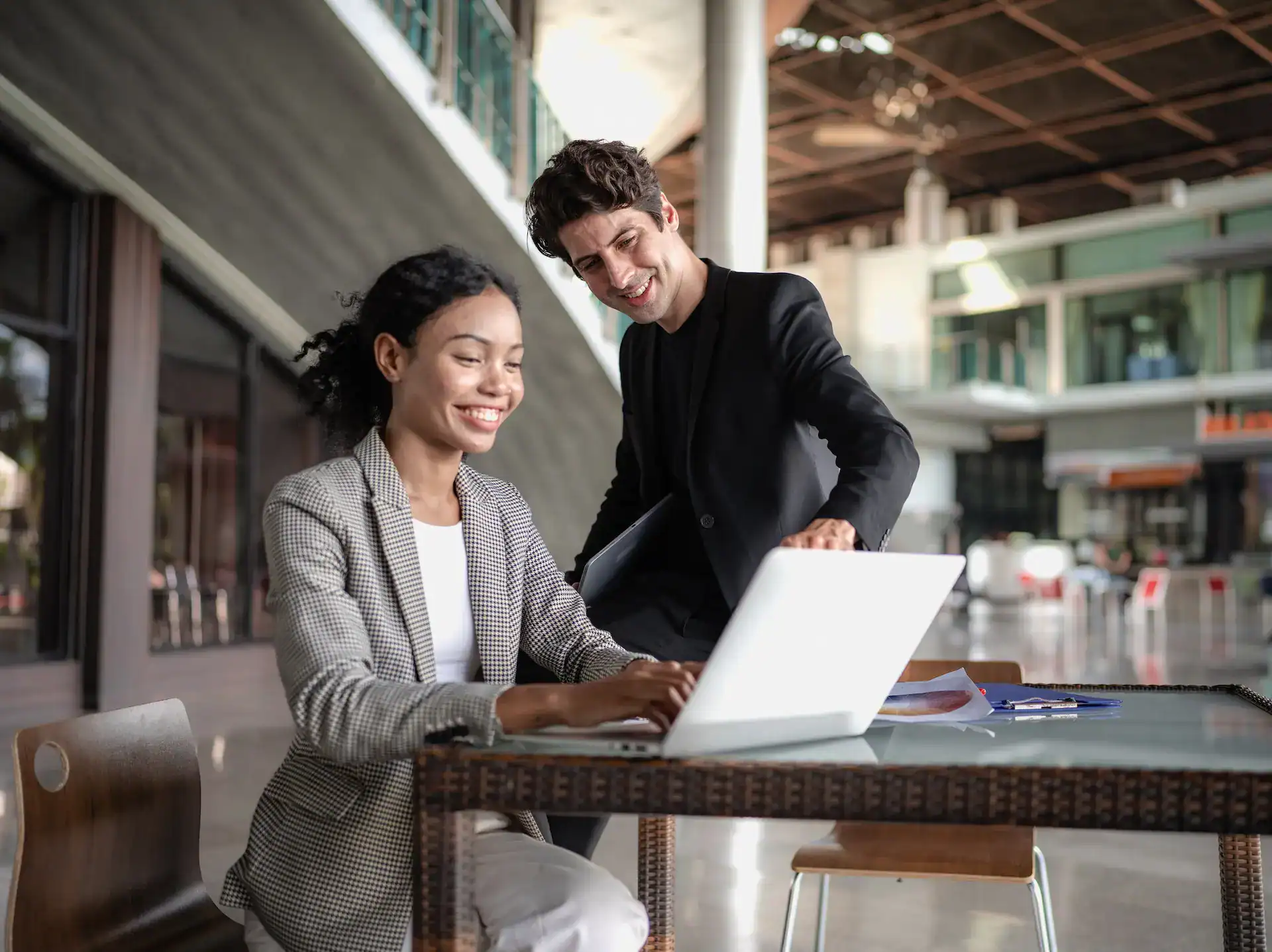 A man and woman collaborate on her laptop, using an AI tool to enhance their work and career outcomes.