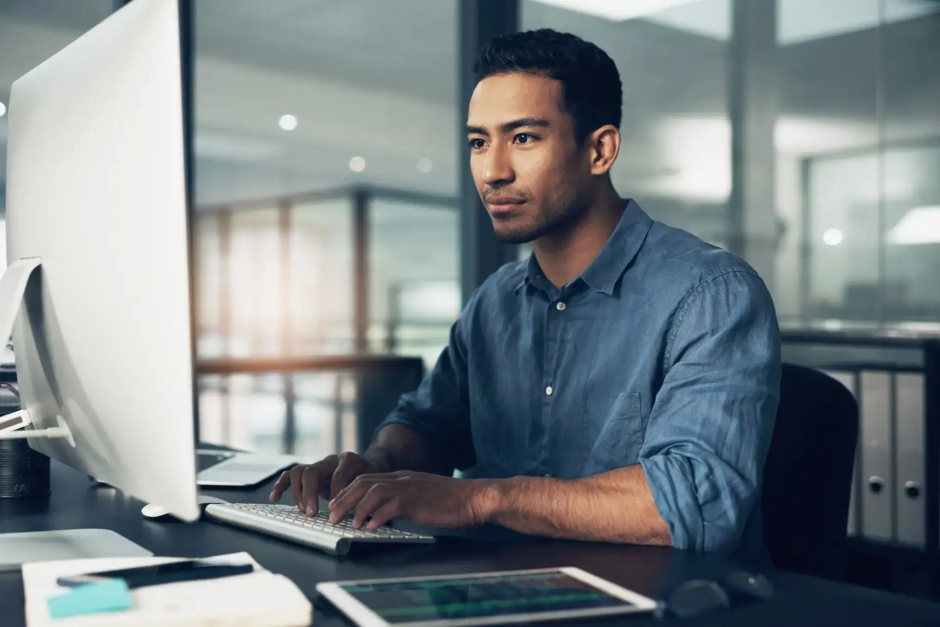 A man typing on his desktop computer as part of his LinkedIn professional development efforts.