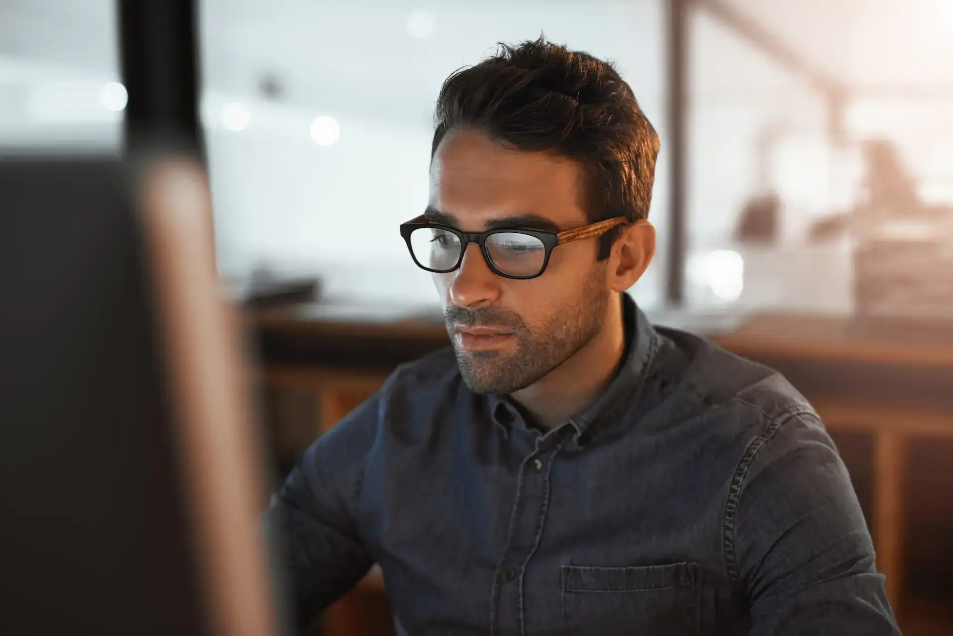 A man with glasses intently looking at a computer screen, representing how his values guide personal development and learning.