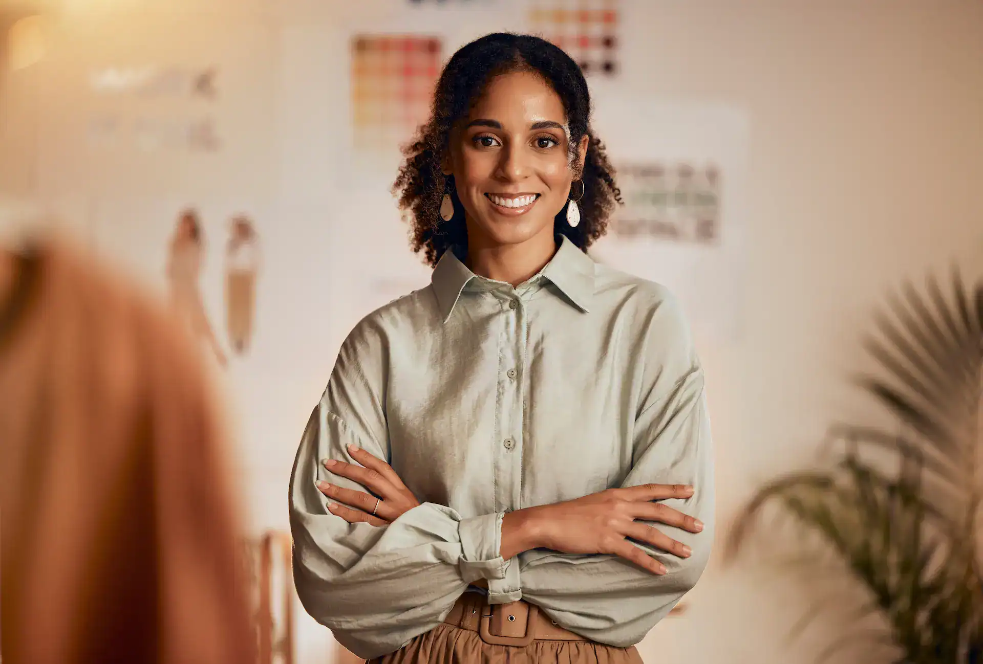 A confident woman stands smiling with her arms crossed, her posture reflecting the values of professionalism and approachability.