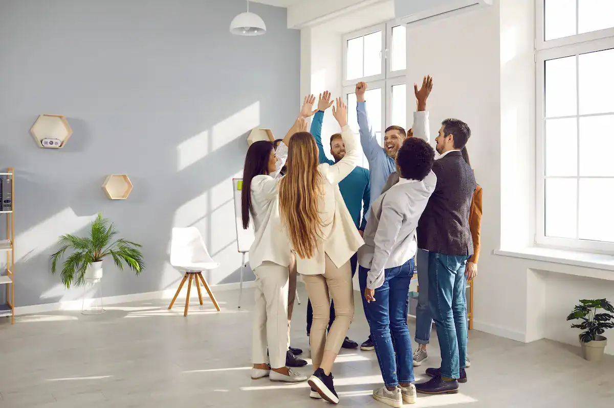 A group of diverse professionals celebrating together in a circle, demonstrating the positive outcome of effective expectation setting in a team.