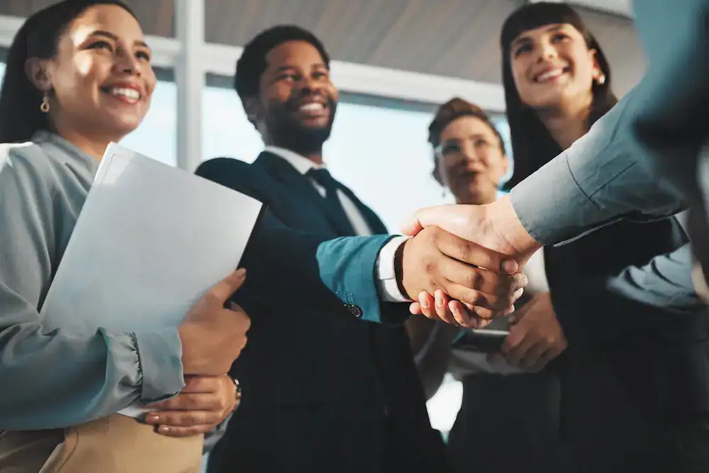 Four people smiling after a successful meeting as part of the hiring process.