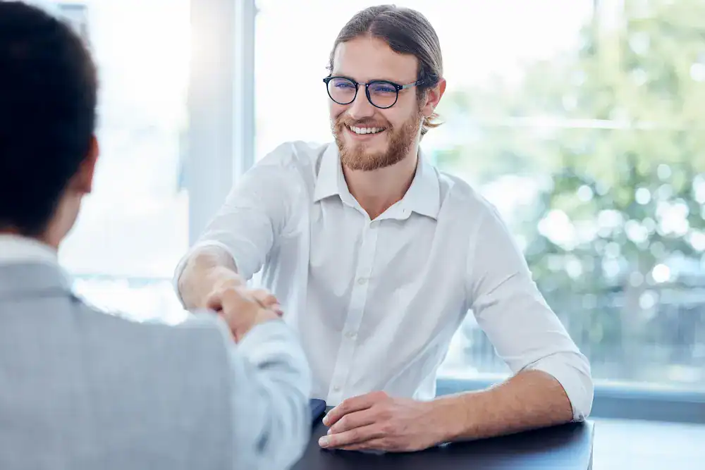 A man in a white shirt shakes hands during the hiring process.