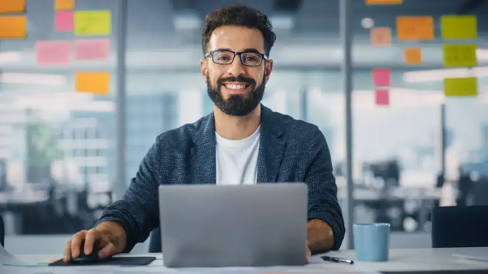 A man sits at a desk smiling, representing a person's ability to learn and grow from mistakes and setbacks.