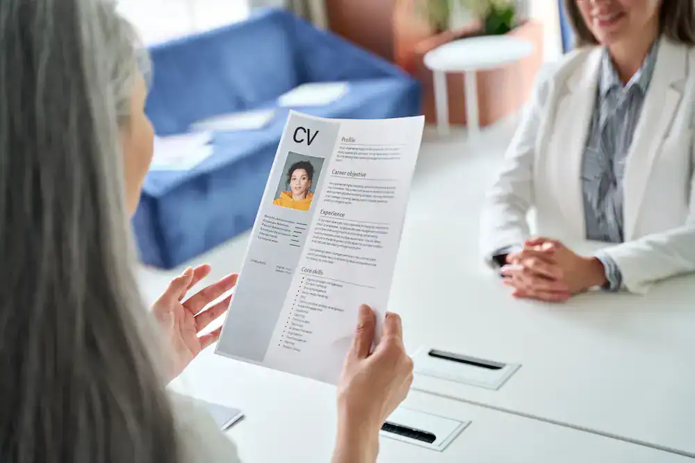 Two women discuss a CV as part of the hiring process.