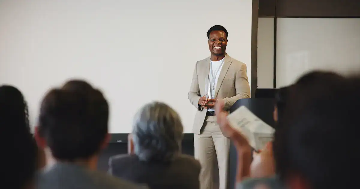 usiness speaker presenting to an audience during a professional conference or corporate event.