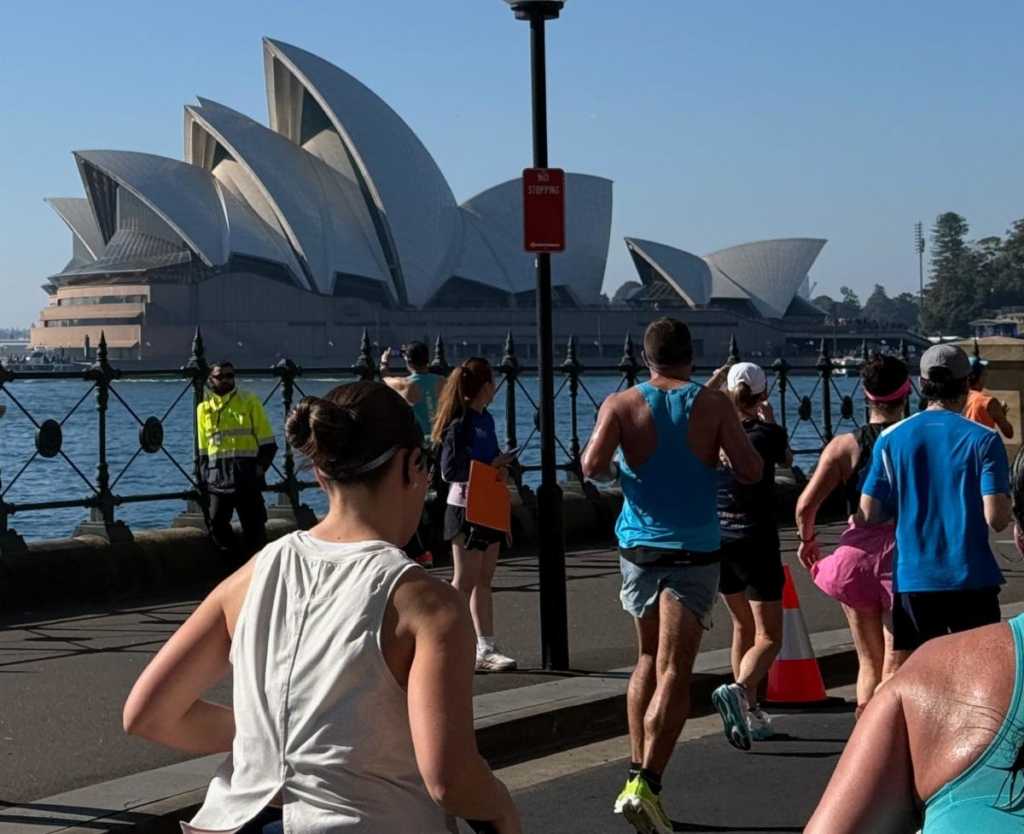 Runners competing in the Sydney Marathon with the Sydney Opera House in the background, illustrating lessons about perseverance, pacing, and the career journey.